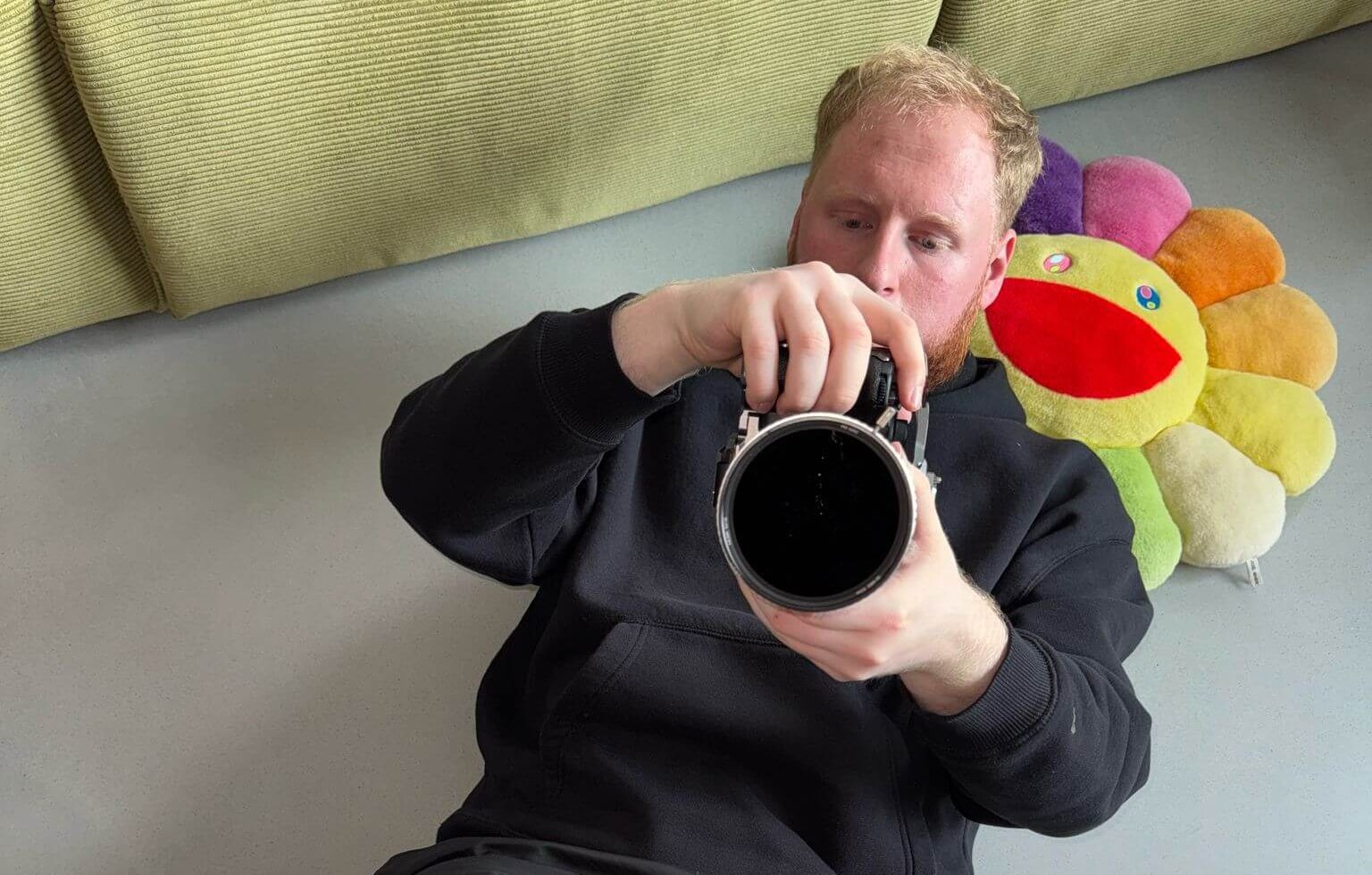 Kameraman Viktor Palko ležiaci na zemi, držiaci fotoaparát pri natáčaní videa pre Vinted.